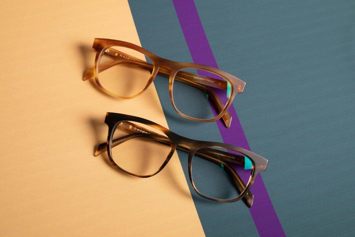 Close-up of two trendy spectacles on vibrant pastel surfaces.