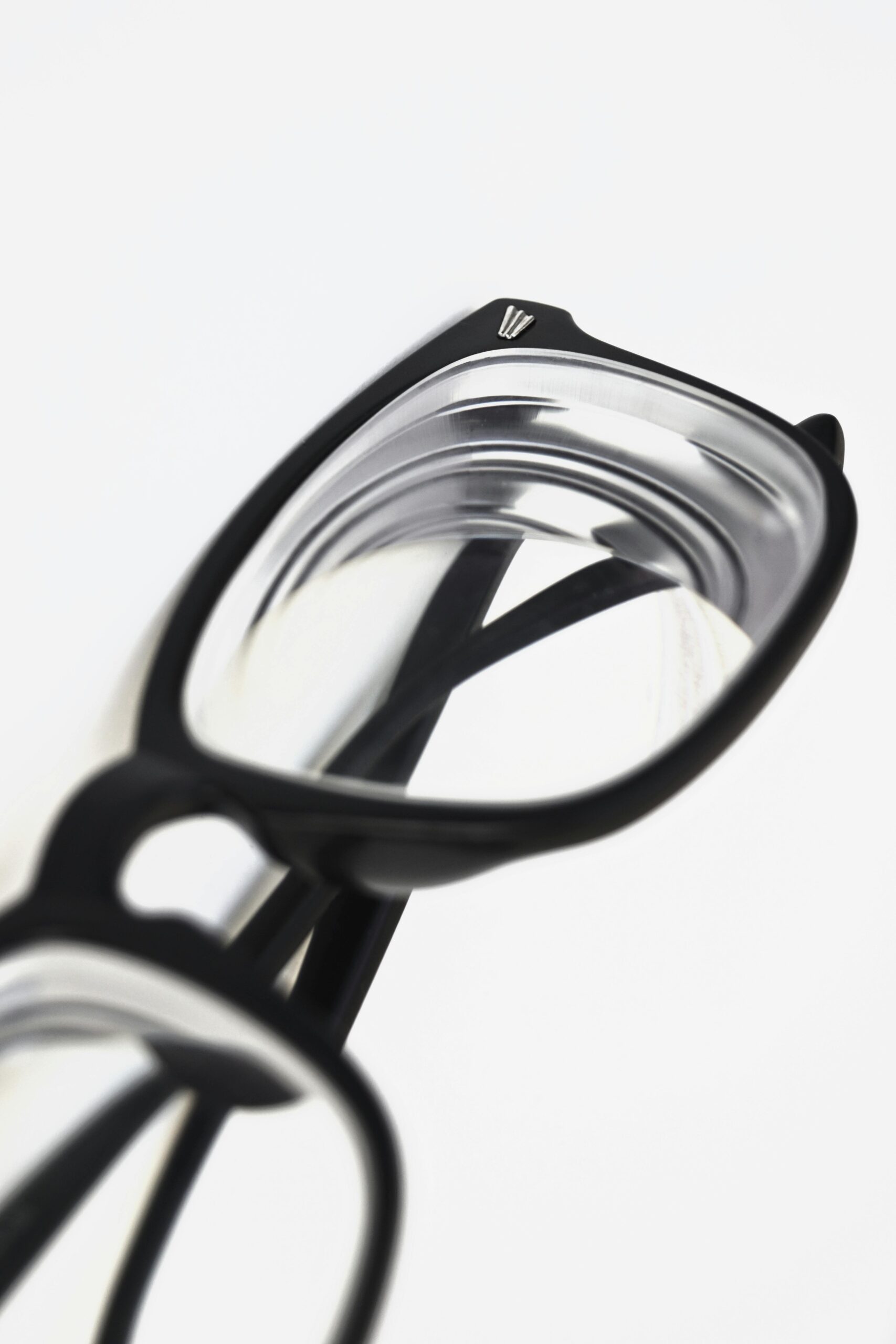 Modern black frame eyeglasses close-up on white surface, showcasing stylish eyewear design.